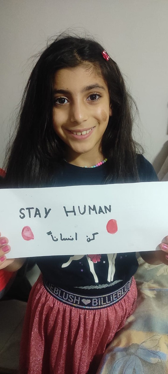 A child holding a Stay Human sign in Gaza